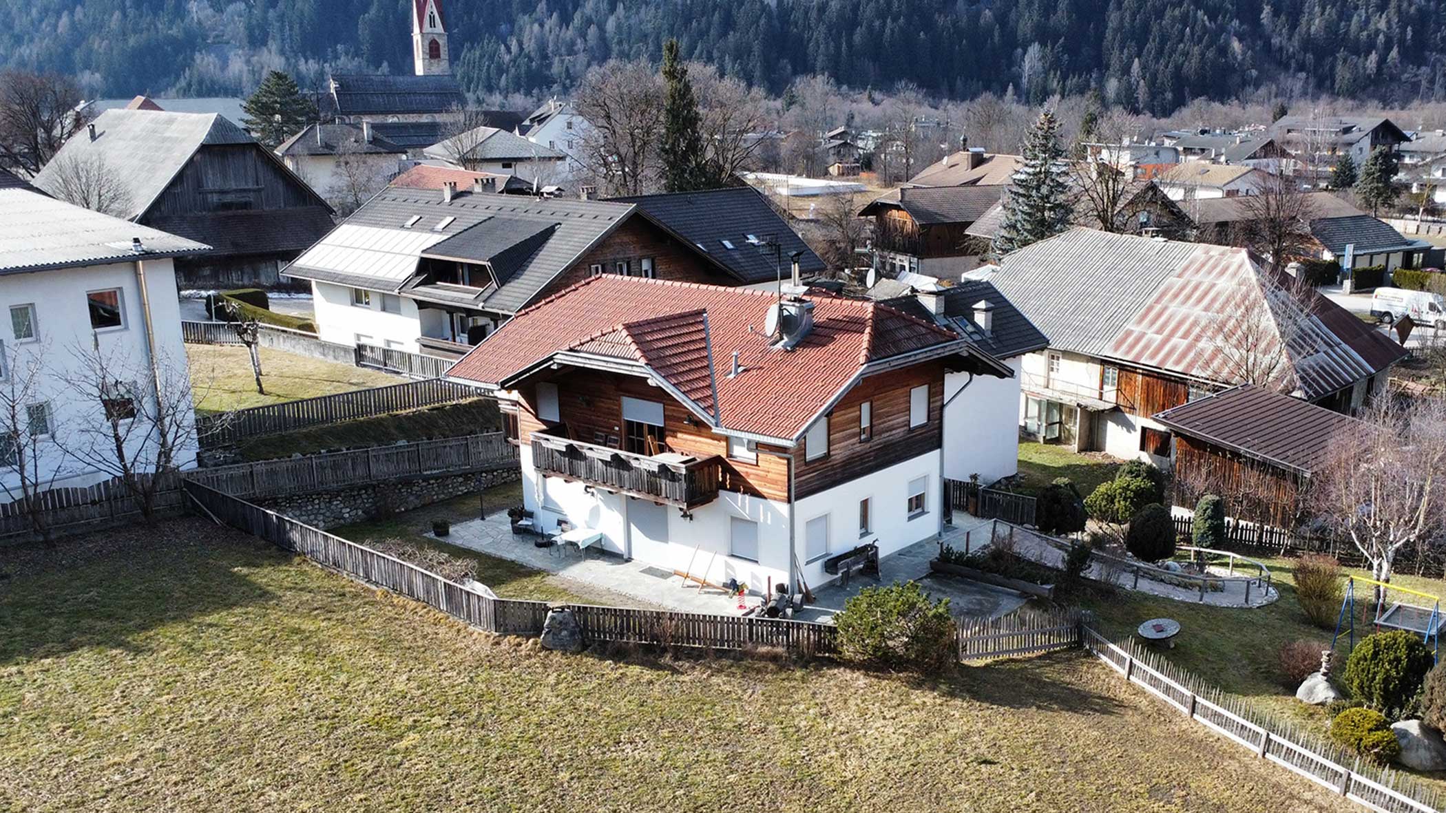 Der Ortnerhof von außen mit dem Ort Gais im Hintergrund
