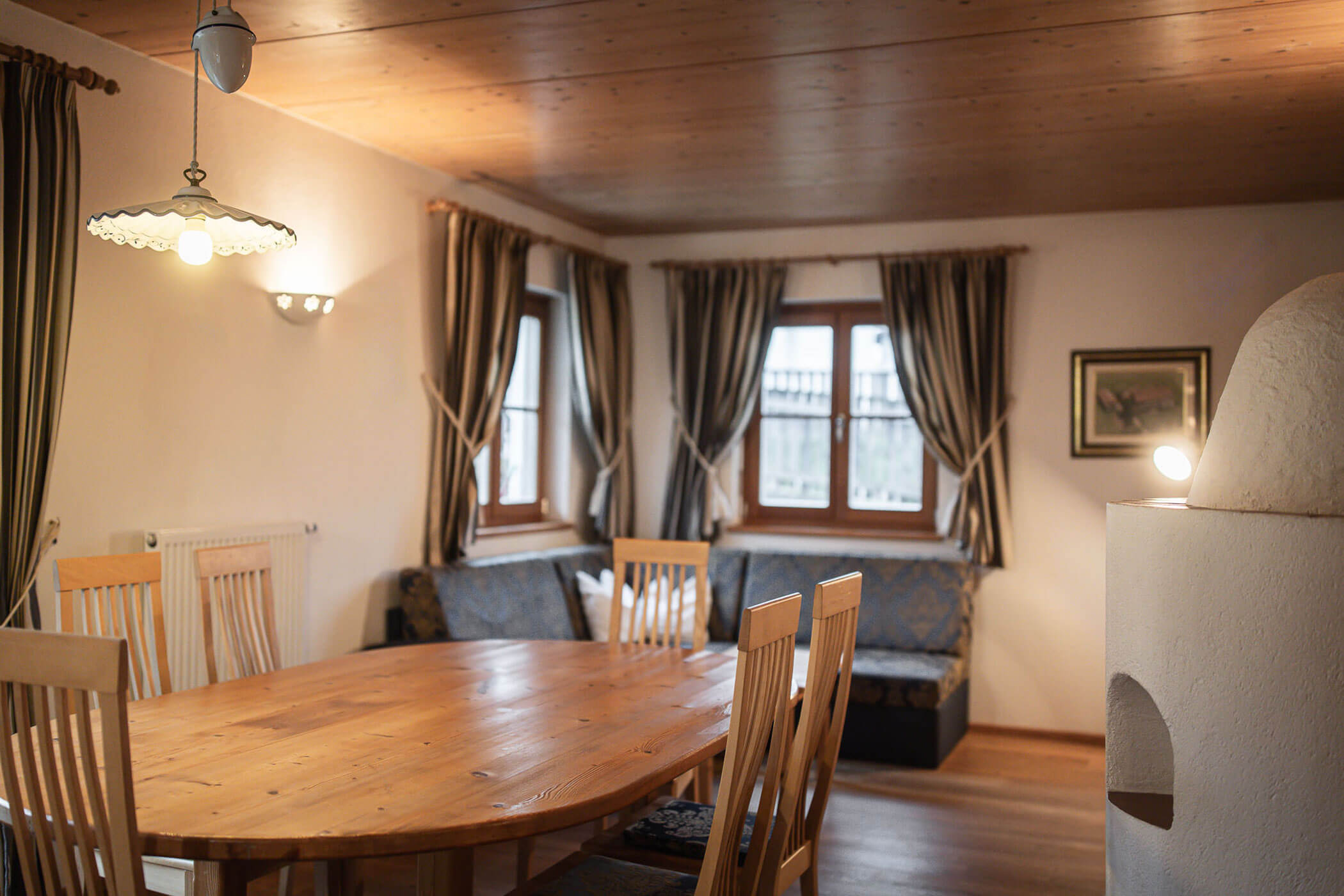 Wohnzimmer mit Esstisch, Sofa und Kaminofen in der Ferienwohnung Apfelblüte - Ortnerhof