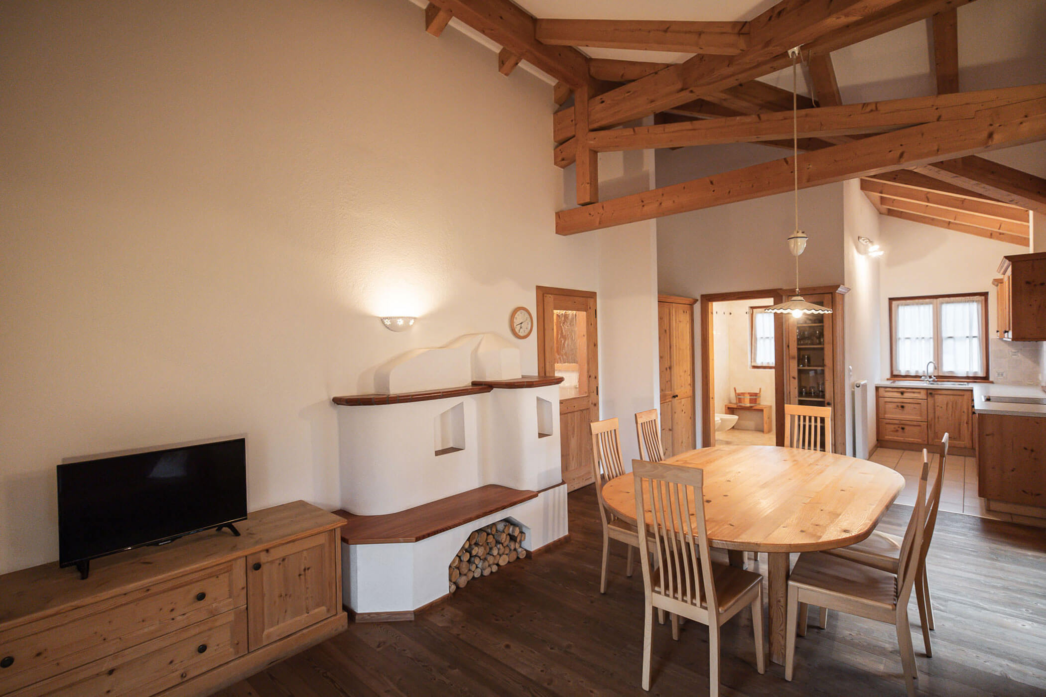 Wohn-Esszimmer mit Esstisch, Ofen und TV in der Ferienwohnung Kirschblüte - Ortnerhof